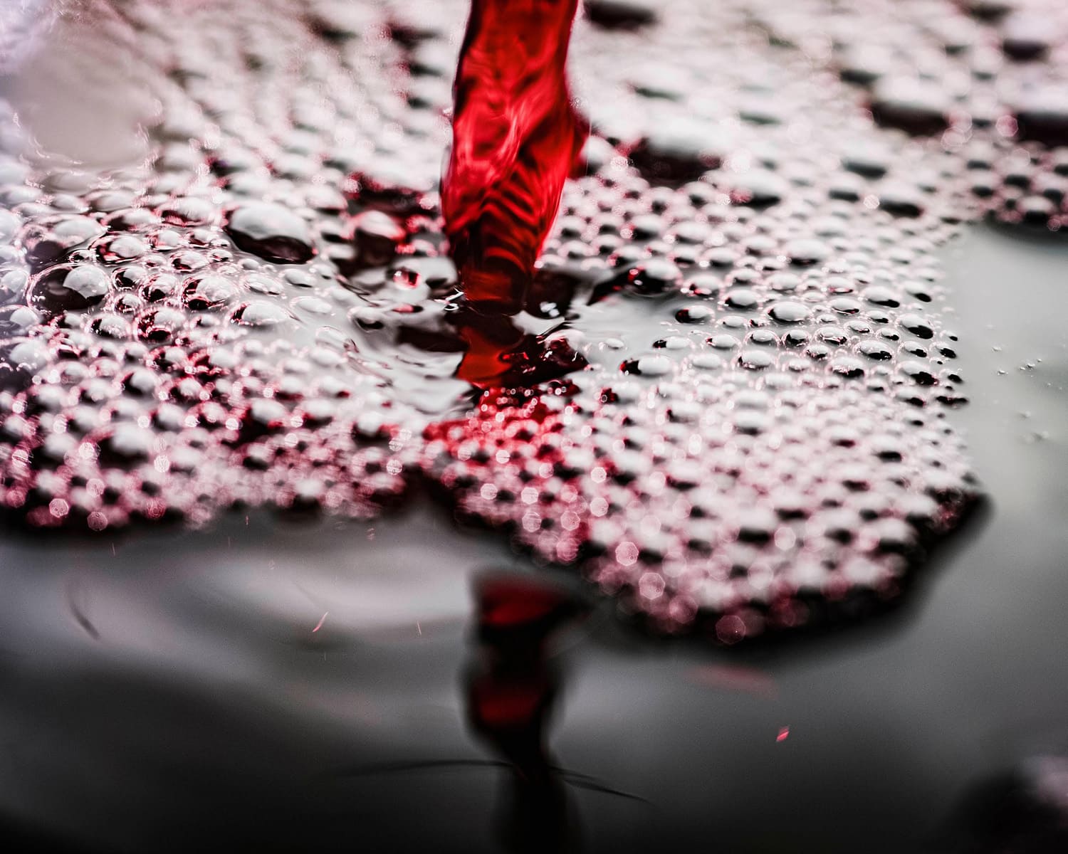 Vin rouge versé avec bulles en gros plan.